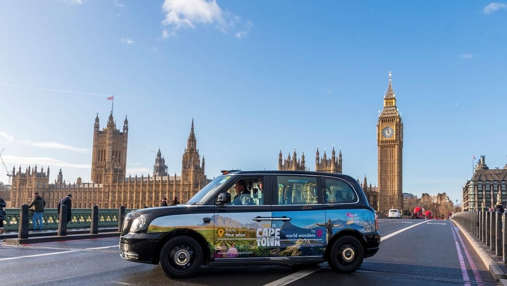 A black cab in London featuring This is Cape Town signage.