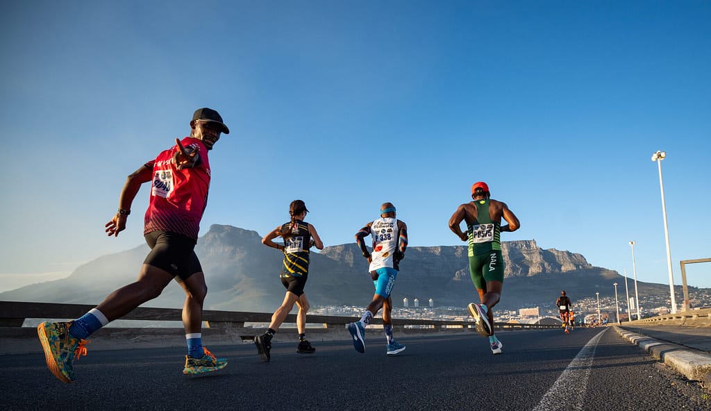 Men and women running on road in Cape Town with view of Table Mountain