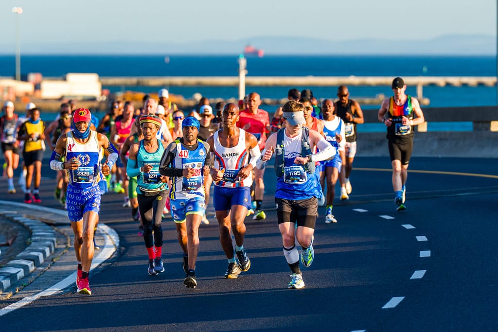 Batch of Cape Town Marathon runners on the Elevated Freeway with the Atlantic Ocean in the distance