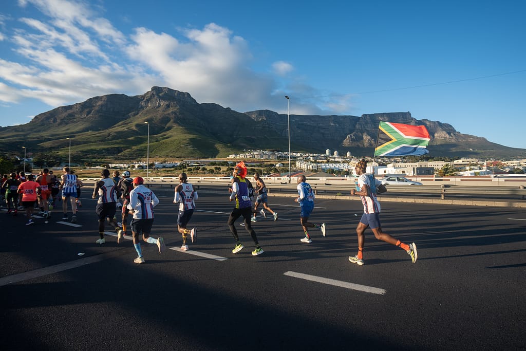 Cape Town Marathon runners on Nelson Mandela Boulevard, Foreshore, with Table Mountain as backdrop. The marathon takes place on 24 May 2026