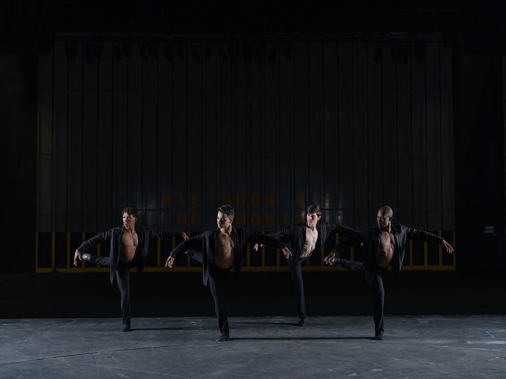 Ballet dancers on stage in black pants and black shirts