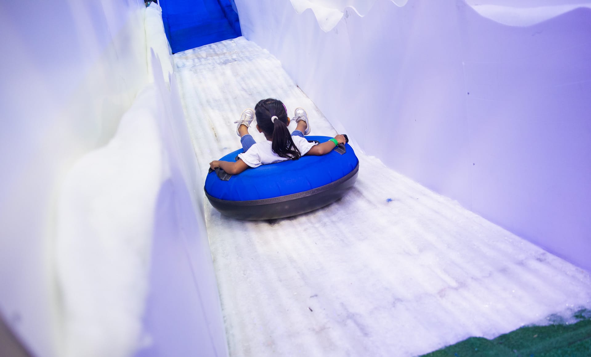 Girl sliding down holiday slides on a blue inflatable tube