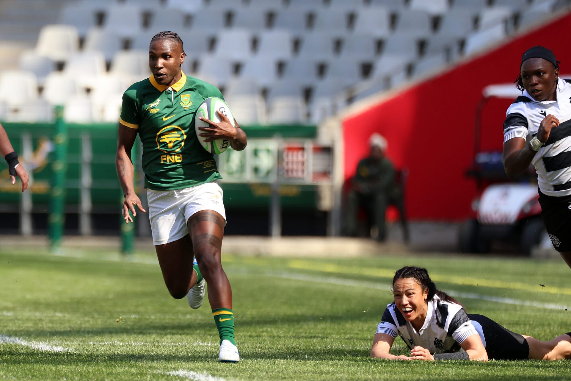Springbok Women winger Ayanda Malinga with ball in hand runs past a fallen Barbarian player