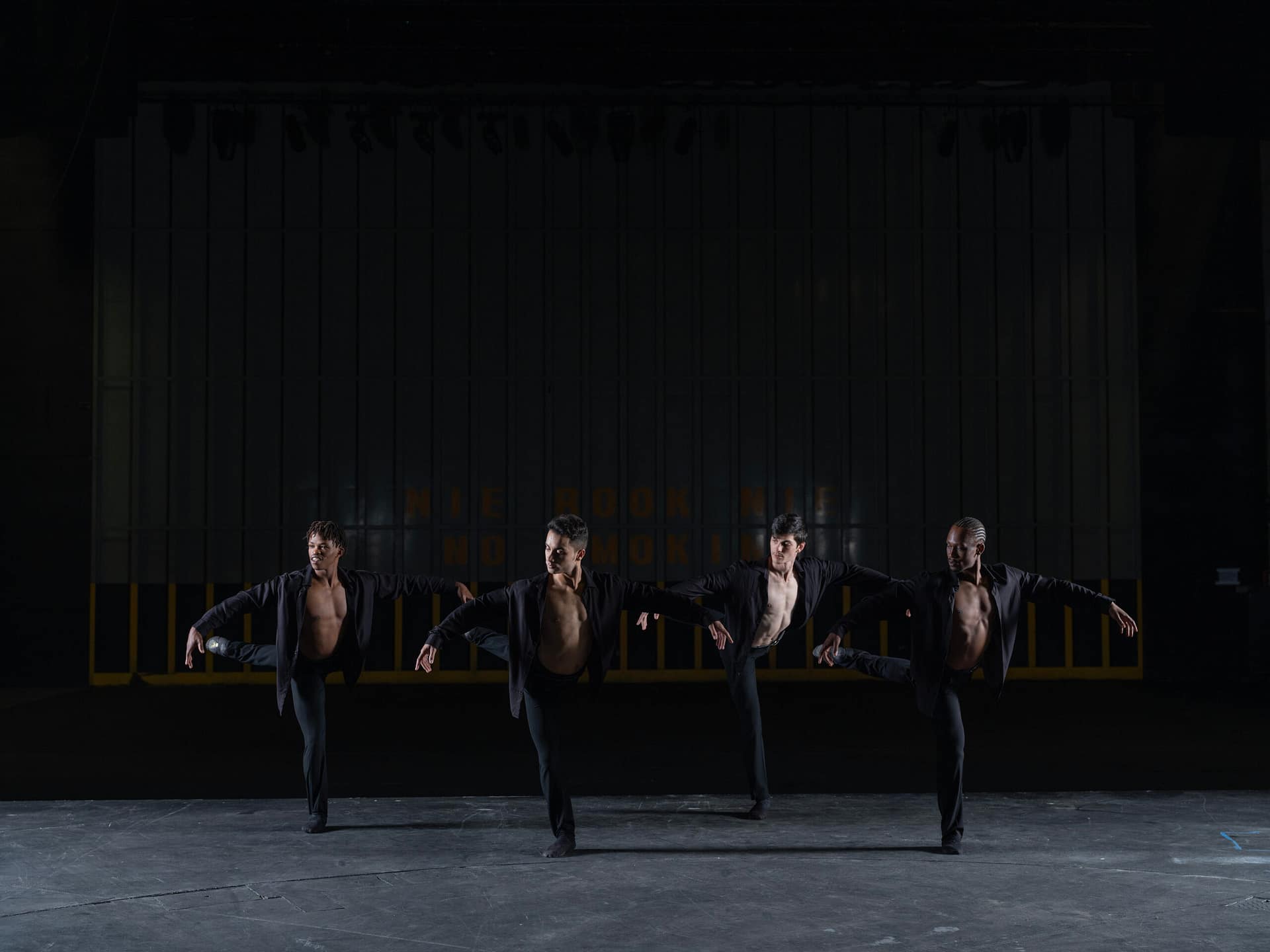 Ballet dancers on stage in black pants and black shirts